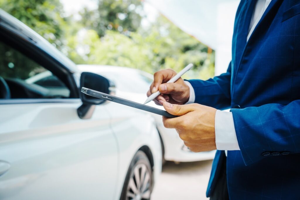 Man writing on tablet with car parked