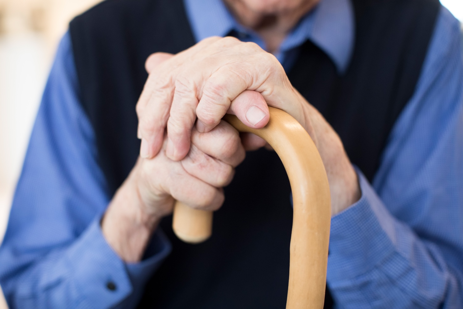 Closeup of older mans hands holding cane