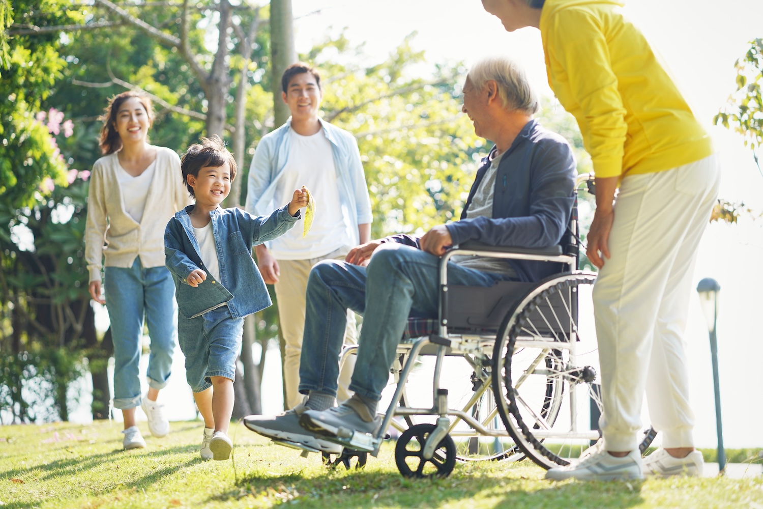 Older man in wheelchair outside with his family