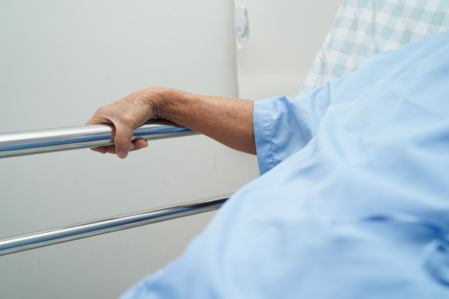 Older patient in hospital bed holding railing