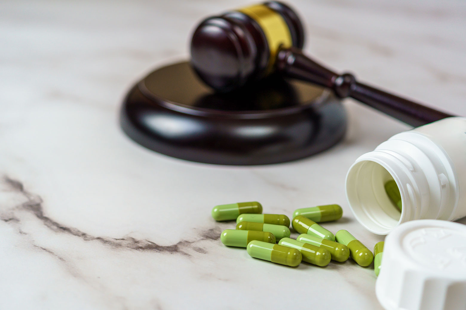 Bottle of pills spilled open with gavel for pharma related legal case