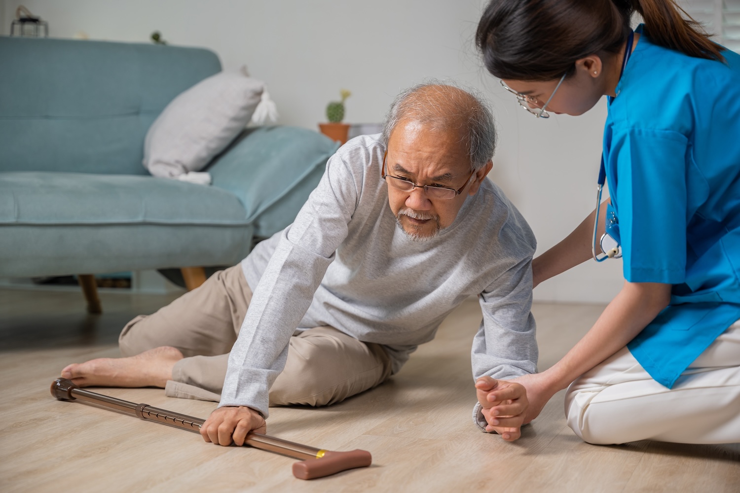 Older man fallen with cane, being helped by younger woman